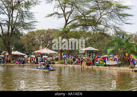 Les personnes bénéficiant de colporter des promenades en bateau sur le lac, de divertissement et des forains peut être vu en arrière-plan, Uhuru Park, Nairobi, Kenya, Afrique de l'Est Banque D'Images