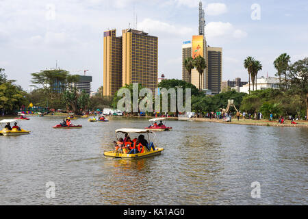 Les personnes bénéficiant de colporter des promenades en bateau ainsi que de s'asseoir près de Lake et à les regarder, Uhuru Park, Nairobi, Kenya, Afrique de l'Est Banque D'Images