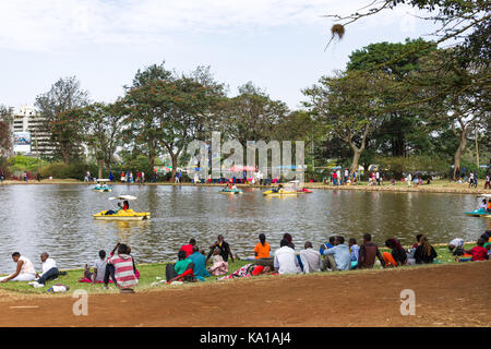 Les personnes bénéficiant de colporter des promenades en bateau ainsi que de s'asseoir près de Lake et à les regarder, Uhuru Park, Nairobi, Kenya, Afrique de l'Est Banque D'Images