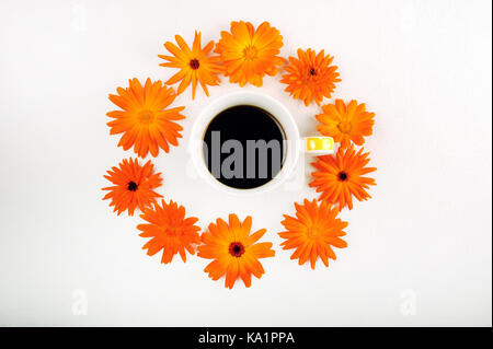 Photo horizontale de cercle de fleurs orange avec tasse de café au milieu. vue d'en haut. calendulas disposées en cercle sur un tissu blanc. copie espace o Banque D'Images