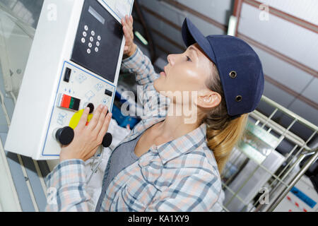 Femme à l'aide d'un panneau de commande à l'usine Banque D'Images