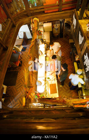 La vue ci-dessus des barmen debout derrière le comptoir du bar et de servir le cunstomer dans le café décoré dans un style en bois. Banque D'Images
