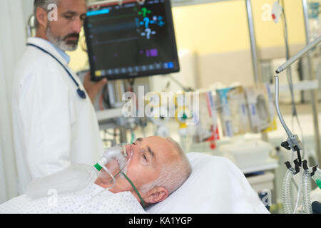 Doctors holding patients masque à oxygène in hospital room Banque D'Images