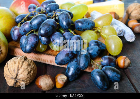 Ensemble de produits d'automne : les raisins, les noix, noisettes, prunes, miel, fromage, raisins, poires, canneberges séchées sur un fond de bois Banque D'Images