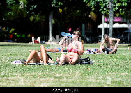 Jeune femme se détendre, prendre le soleil et l'eau potable sur l'Esplanade, Cairns, Far North Queensland, Queensland, Australie, FNQ Banque D'Images