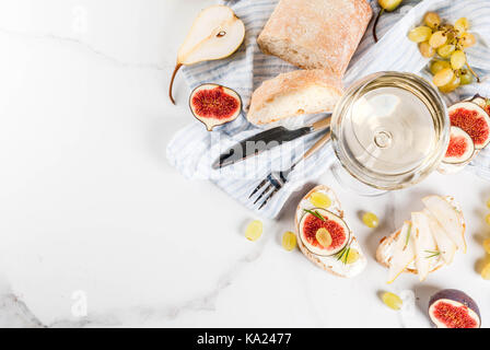 Des sandwichs de ricotta ou de fromage à la crème, ciabatta, figues, poires, raisin, noix et miel sur table table en marbre blanc, avec un verre de vin copy space Banque D'Images