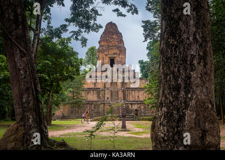 Femme vélo, temple de Baksei Chamkrong, Parc archéologique d'Angkor, Siem Reap, Cambodge Banque D'Images