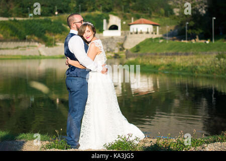 Bride and Groom hugging émotionnel en face d'un lac Banque D'Images