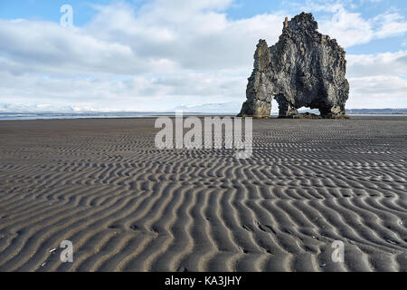 Formation en pierre sur le sable volcanique foncé sur le fond du ciel bleu avec des nuages. il est hvitserkur durant la marée basse en Islande. horizontale. Banque D'Images