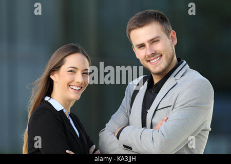 Couple de cadres posing looking at camera debout sur la rue avec un immeuble de bureaux à l'arrière-plan Banque D'Images