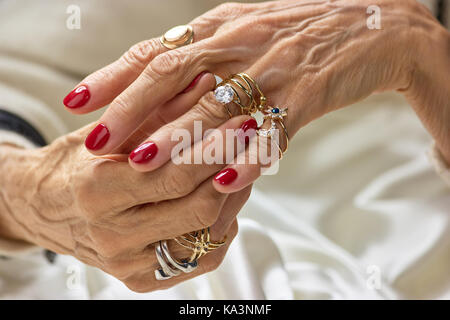 Les mains avec des anneaux d'or. senior woman mains avec de beaux ongles rouge portant un grand nombre de bagues d'or. womens la richesse et la beauté. Banque D'Images