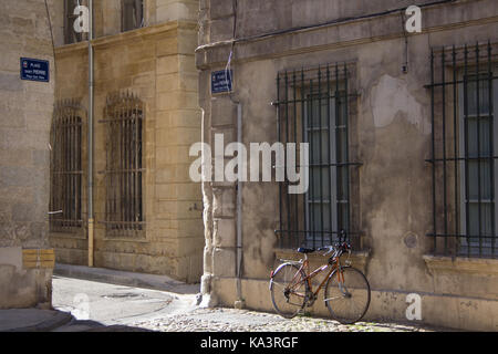 Scène de rue à Avignon, France. un seul vélo solitaire se dresse contre l'immeuble le long de la place Saint Pierre. Banque D'Images