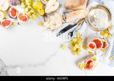 Des sandwichs de ricotta ou de fromage à la crème, ciabatta, figues, poires, raisin, noix et miel sur table table en marbre blanc, avec un verre de vin copy space Banque D'Images