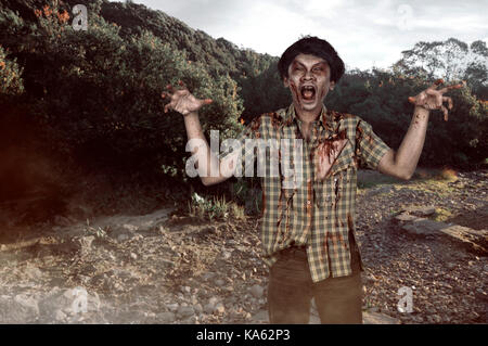 Effrayant zombie asiatique homme avec visage blessé et griffes main dans un endroit abandonné Banque D'Images