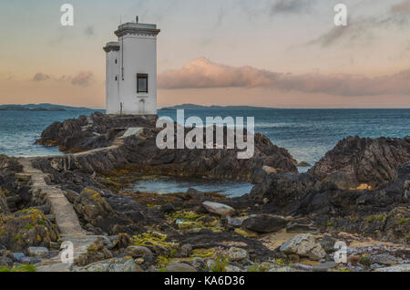 Le phare de Port Ellen, carraig fhada phare dans lumière du soir après le coucher du soleil avec de jolies couleurs sur le skye avec des falaises et des algues en premier plan, port Banque D'Images