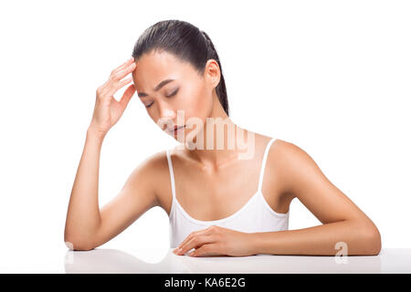 Young Asian woman ayant des maux de tête. L'emplacement de fille avec les yeux fermés et maladive. expression de l'émotion la douleur, le stress et la fatigue. modèle féminin isolées Banque D'Images