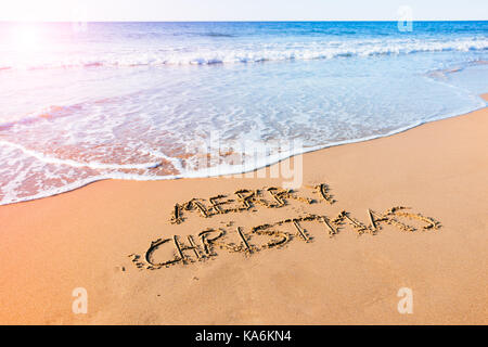 Joyeux Noël écrit dans le sable au bord de la mer sur la plage Banque D'Images