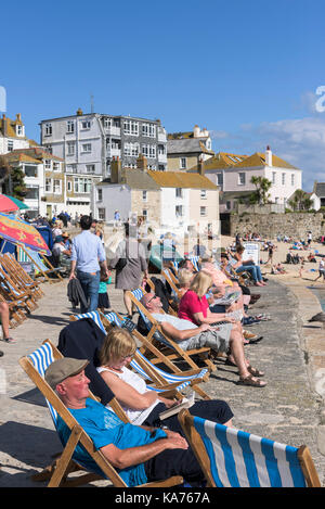 St Ives - vacanciers, de vous détendre dans des chaises longues sur le quai à St Ives harbour beach, à Cornwall. Banque D'Images