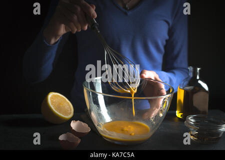 Battre les jaunes dans un bol en verre, fouetter avec citron et huile d'olive close-up l'horizontale Banque D'Images