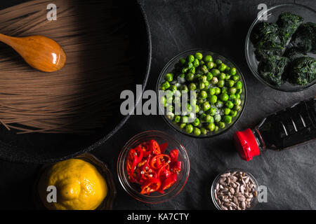 Nouilles de sarrasin dans une poêle, les pois congelés, citron, les graines de tournesol dans un bol l'horizontale Banque D'Images