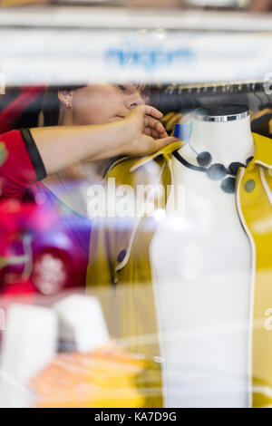 Yound femme adulte taille sur l'étiquette de contrôle tandis que la photographie de rue. chiffons commercial tourné à travers l'avant vitrine Banque D'Images