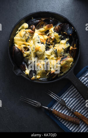 Les moules avec une sauce au fromage dans un poêlon, serviette et verticale des fourches Banque D'Images