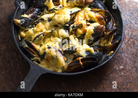 Poêle avec moules sous de la sauce au fromage sur un fond brun horizontale vue latérale Banque D'Images