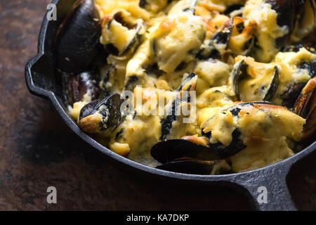 Poêle avec moules sous de la sauce au fromage sur un fond brun close-up l'horizontale Banque D'Images