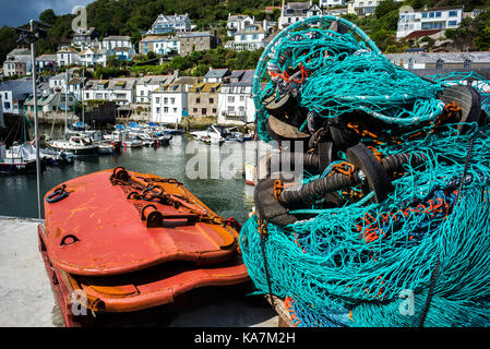 Les filets de pêche dans les boîtes en plastique bleu sur quai avec harbor cottages cornwall en arrière-plan Banque D'Images