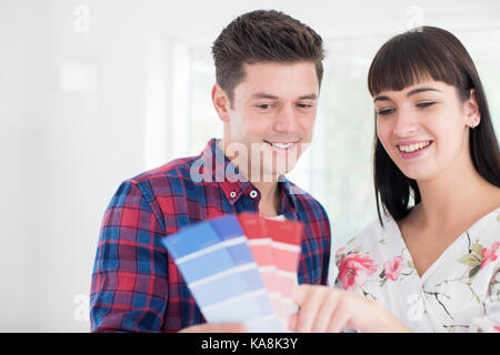 Couple looking at paint swatches in new home Banque D'Images