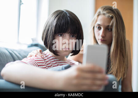 Teenage girl with friend intimidé par message texte Banque D'Images