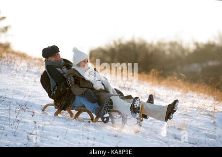 Beau couple sur un traîneau s'amusant, journée d'hiver. Banque D'Images