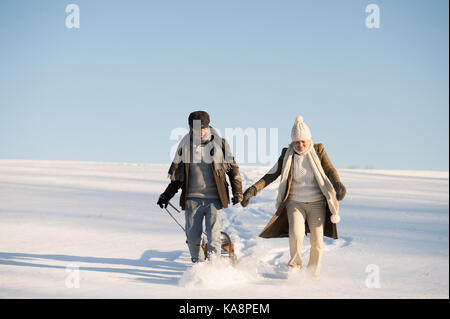 Beau couple sur un marche en tirant le traîneau, journée d'hiver. Banque D'Images