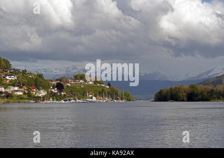 Vue sur la ville plus de hardangerfjorden littoral avec mountians enneigés dans le lointain pendant la tempête Banque D'Images