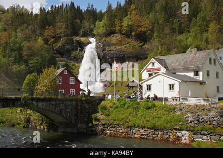 Cascade de Steinsdalsfossen dans la rivière Steine, paysage pittoresque avec cascade surmontée par les montagnes et les maisons traditionnelles norvegiennes, scandinaves Banque D'Images