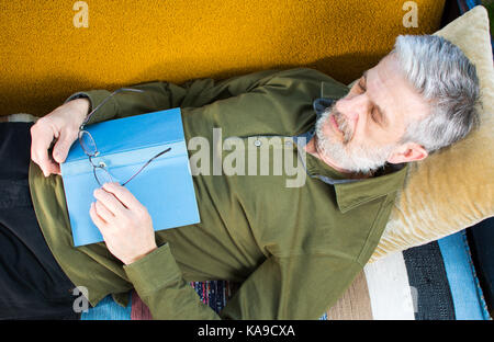 Senior man sleeping avec livre sur un lit dans l'arrière-cour Banque D'Images