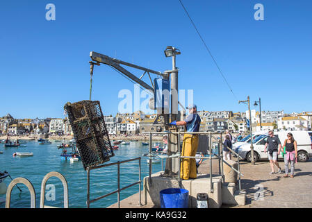 L'industrie de la pêche St Ives - un pêcheur à l'aide d'un palan pour décharger des casiers à homard crabe sur Smeaton's Pier à St Ives en Cornouailles. Banque D'Images