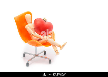 Simulacre en bois avec coeur rouge s'asseoir sur le fauteuil orange Banque D'Images