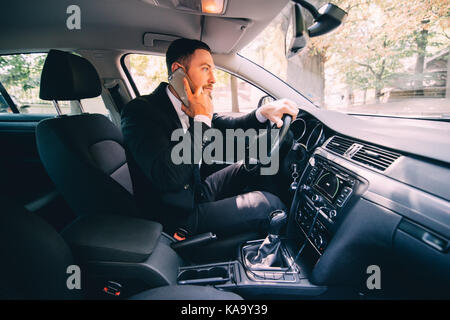 L'homme d'affaires parler pilote voiture téléphone blanc Banque D'Images