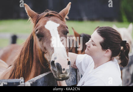 Jeune femme est de flatter un cheval sur une ferme dans le Kentucky Banque D'Images