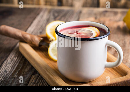 Boire du thé de fruits rouges, de tranches de citron en blanc mug rustique sur table en bois, bain de boissons d'hiver Banque D'Images