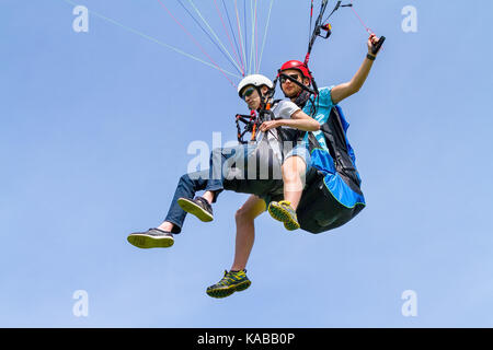 Instructeur de parapente et garçon flottant dans le ciel bleu Banque D'Images