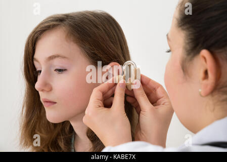 Close-up de médecin l'insertion de l'aide auditive dans l'oreille d'une fille Banque D'Images