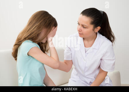 Femme médecin dans labcoat pleurer à l'hôpital du patient réconfortant Banque D'Images