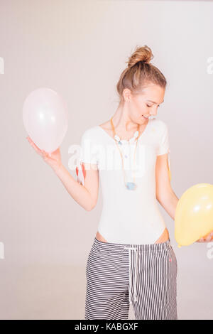 Fille blonde avec des ballons et confettis Banque D'Images