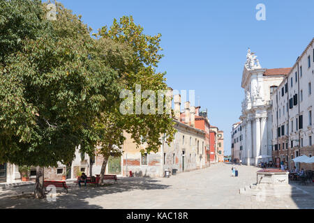 Campo dei Gesuiti, Cannaregio, Venise, Vénétie, Italie avec des touristes à l'air ouvert restaurants et sous les arbres en regardant vers l'Église et la Refugee Banque D'Images