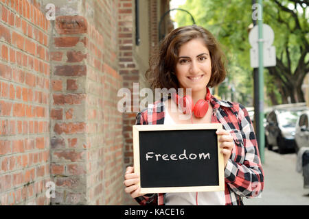 Young Beautiful woman holding tableau avec texte "liberté". à l'extérieur. Banque D'Images