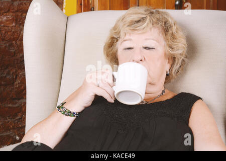 Portrait d'une vieille femme de boire du café et assis sur table. à l'intérieur. Banque D'Images