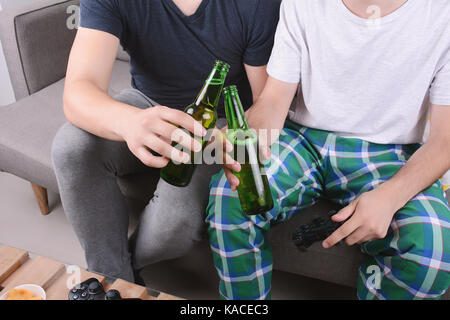 Portrait de deux amis jouant des jeux vidéo, de manger des collations et de la bière drinkng. à l'intérieur. Banque D'Images