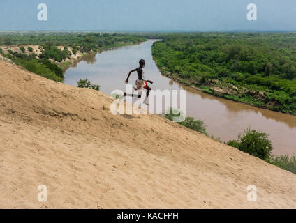 La tribu Karo garçon sautant en face de la rivière Omo, vallée de l'Omo, Ethiopie, Korcho Banque D'Images